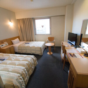 Twin beds in a guest room with desk and TV