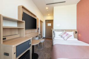 Twin beds beside desk and wall-mounted television