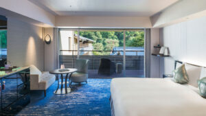 Gästezimmer mit Bett, Stühlen und Balkonblick