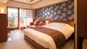 Chambre avec grand lit et coin salon près de la fenêtre