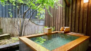 Private wooden outdoor bath with bamboo fence and tree