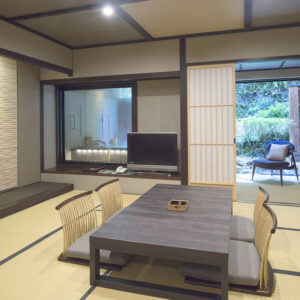 榻榻米客房，配有矮桌、和室座椅和通往庭院的门