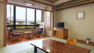 Chambre en tatami avec table basse, chaises et banquette près de la fenêtre