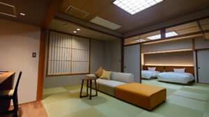 Chambre en tatami avec canapé et lits dans l’espace attenant
