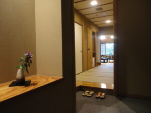 Couloir d’entrée d’une chambre en tatami avec des chaussons et un vase de fleurs