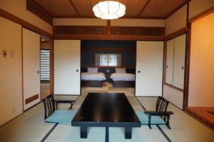 Chambre en tatami avec table basse et chaises, lits au fond