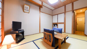 Chambre en tatami avec table basse, chaises de sol et télévision
