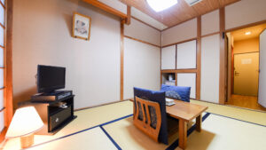 Chambre en tatami avec table basse, chaises de sol et télévision