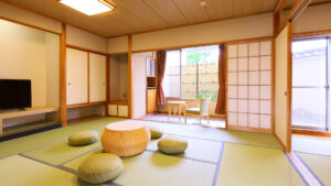 Camera in tatami con tavolo basso, cuscini da pavimento e sedie