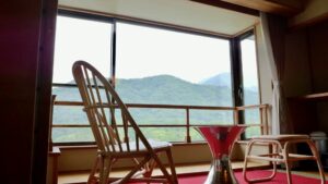 椅子とテーブルのある客室の窓から望む山の景色