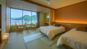 Zwei Einzelbetten in einem Tatami-Zimmer mit Sitzbereich am Fenster