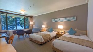 창가 옆 의자가 놓인 객실의 트윈 침대