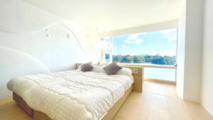 Letto matrimoniale accanto a una grande finestra con vista sull’acqua