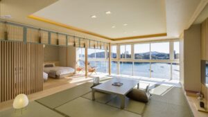 Camera in tatami con tavolino basso accanto ai letti e grandi finestre