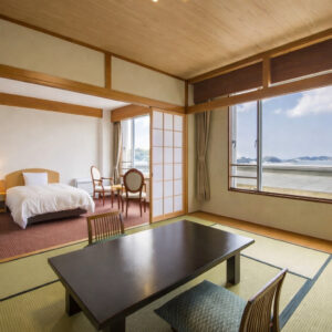 Camera in tatami con tavolo basso, sedie e zona letto
