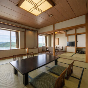 Camera in tatami con tavolo basso, cuscini da pavimento e sedie