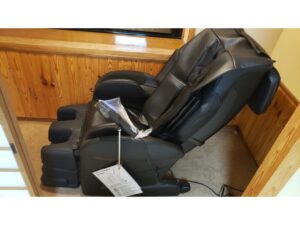木のコーナーに置かれた黒いマッサージチェア