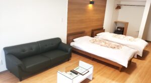 ソファと小さなテーブルがあるツインベッドの客室