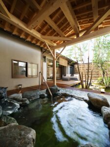 Bain privé extérieur en roche sous un toit en bois