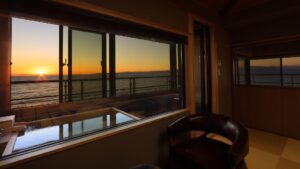 Vue sur le coucher de soleil sur l’océan depuis la fenêtre d’une chambre en tatami