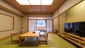 Chambre de style tatami avec table basse, chaises et télévision