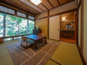 Chambre en tatami avec table basse et fenêtre sur la forêt