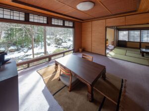 Coin salon en tatami près d’une grande fenêtre avec vue sur un paysage enneigé