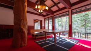 Coin salon en tatami avec table basse près de fenêtres donnant sur la forêt