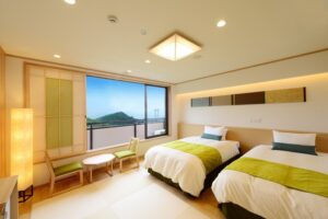 Twin beds beside a window with mountain view