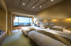 Lits jumeaux dans une chambre en tatami avec fenêtre vue sur l’océan