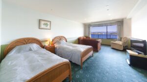 Due letti singoli in una camera con divano e finestra