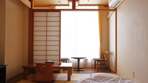 Chambre en tatami avec table basse, chaise de sol et banquette près de la fenêtre