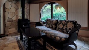 Blumensofa und Tisch neben einem Ofen und Rundfenster
