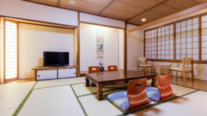 Chambre en tatami avec table basse, chaises de sol et télévision