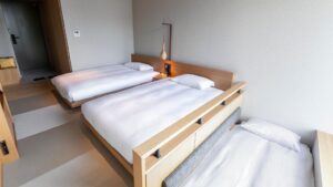 Drei niedrige Betten mit weißer Bettwäsche in einem Gästezimmer