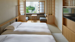 Zwei Einzelbetten in einem Tatami-Gästezimmer mit Sitzgelegenheit am Fenster
