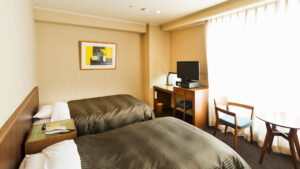 Twin beds in a guest room with desk and chairs