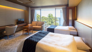 Twin beds in a guest room with sofa and balcony.