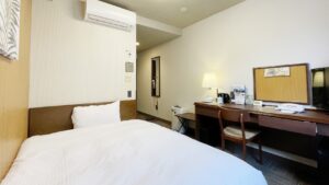 Single bed beside desk and chair in guest room