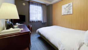 Single bed beside desk and window in guest room