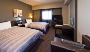 Twin beds in a guest room with desk and TV