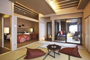 带有榻榻米休息区、床和窗边椅子的客房