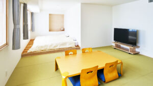 ローテーブル、椅子、台付きベッドのある畳の部屋