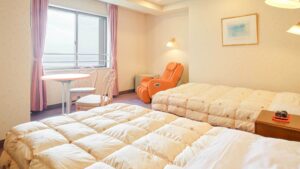 客室の窓際に椅子のあるツインベッド