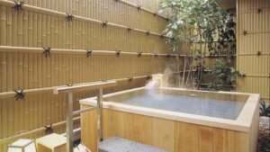 Private wooden open-air bath beside bamboo fence