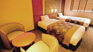 Twin beds beside two chairs and a small table