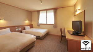 Twin beds in a guest room with desk and TV