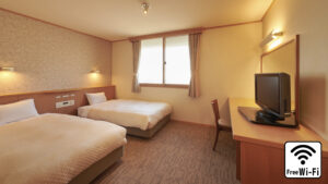 Twin beds in a guest room with desk and TV
