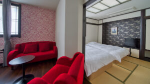 Letto accanto all’area tatami e alla zona salotto con divano rosso
