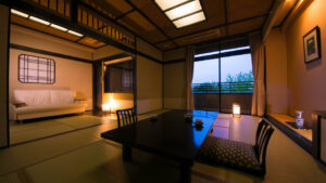 Camera in tatami con tavolo basso, sedie e zona letto